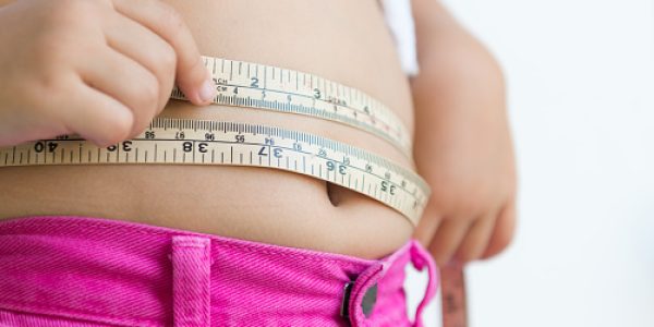 cute girl measuring her belly with measurement tape at home